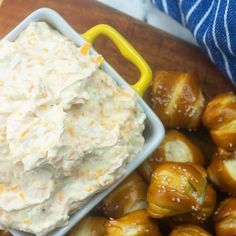 there is a bowl of dip next to some pretzels