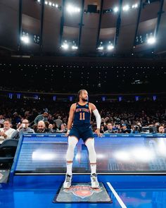 a man standing on top of a basketball court in front of an arena full of people