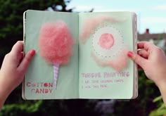 someone is holding an open book with cotton candy on it and the pages are pink