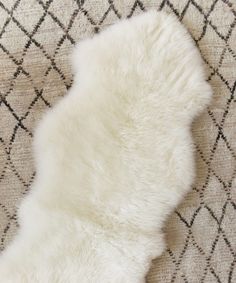 a white sheepskin rug on top of a carpet with black and white squares in the background