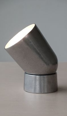 a silver object sitting on top of a table next to a white wall and floor