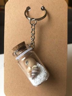 a glass jar filled with white sand and a keychain hanging from it's side