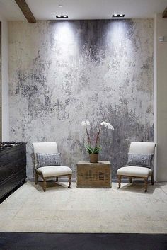 two white chairs sitting in front of a large wall