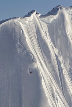 a person skiing down the side of a snow covered mountain