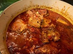 a pot filled with meat and sauce on top of a stove