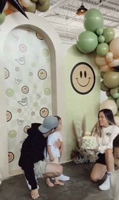 a group of people that are standing in front of a wall with balloons on it