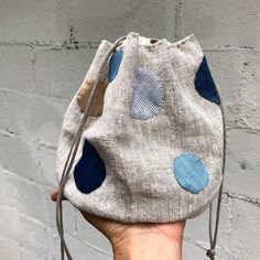 a hand holding a small purse with blue dots on it