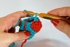 two hands holding crochet hooks and knitting yarn on the end of an object