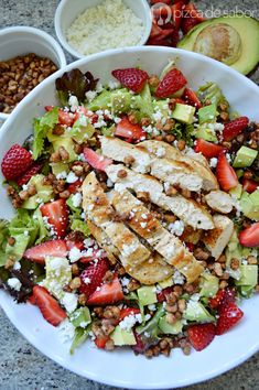 a salad with chicken, strawberries, avocado and nuts