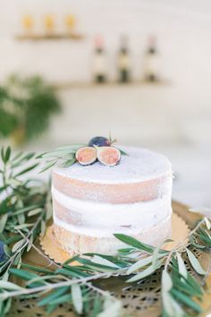 a wedding cake with figurines on top sits on a plate surrounded by greenery