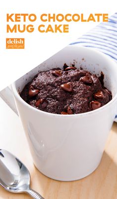 a white bowl filled with chocolate cake on top of a wooden table next to a spoon