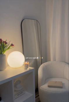 a white chair sitting in front of a mirror next to a vase filled with flowers