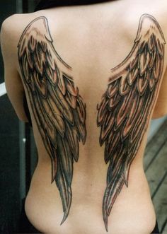 the back of a woman's body with angel wings tattoo on her upper half