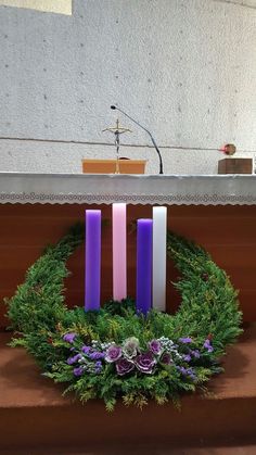 wreath with purple and white candles in front of a church alter, surrounded by greenery