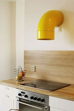 a kitchen with an oven, sink and yellow light hanging from the wall above it