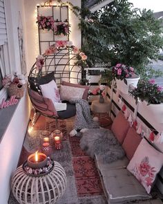 the balcony is decorated with pink and white flowers, candles, and wicker furniture