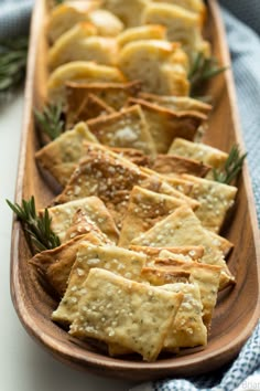 crackers with rosemary sprigs in a wooden dish on a blue and white towel