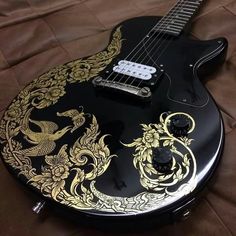 a black and gold guitar sitting on top of a bed