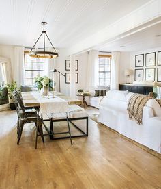 a living room filled with furniture and lots of windows in the wall next to a wooden floor