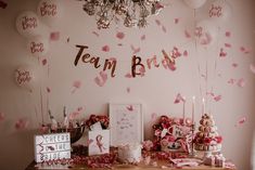 a table topped with lots of balloons and confetti next to a wall that says team boss