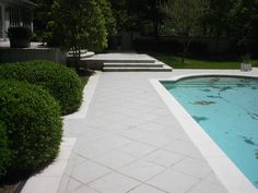 an empty swimming pool in the middle of a garden with steps leading up to it