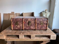 two old suitcases sitting on top of a wooden pallet in front of boxes