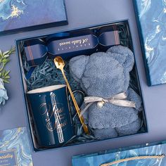 a blue gift box with a teddy bear and coffee cup in it, along with other items