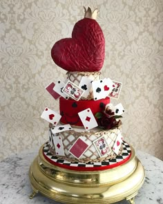 a three tiered cake decorated with playing cards and a red heart on the top