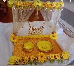 a table topped with yellow plates and flowers on top of a white cloth covered bed