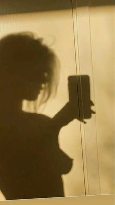 the shadow of a woman holding a cell phone