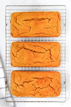 three orange muffins cooling on a wire rack