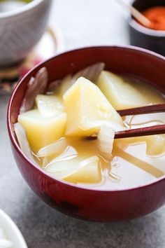 a red bowl filled with soup and chopsticks