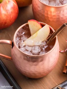 two copper mugs filled with ice and apples