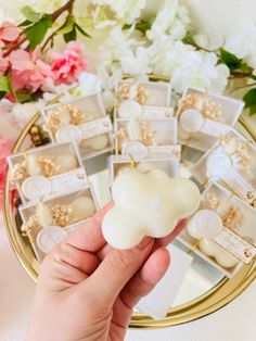 a hand holding a small piece of white soap in front of a mirror with flowers on it