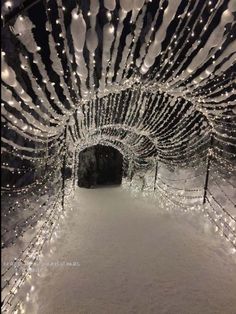 the inside of a tunnel covered in snow with christmas lights on it's sides