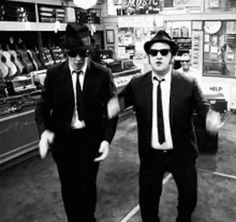 two men in suits and hats are walking down the street