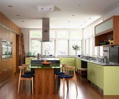 a kitchen with wooden floors and green cabinets, along with a center island in the middle