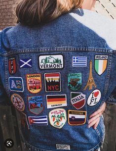 the back of a woman's jean jacket with patches and flags on it,