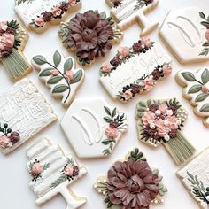 many decorated cookies with flowers and leaves on them are arranged in the shape of letters