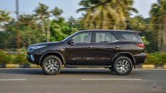 a black suv driving down the road with palm trees in the background