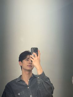 a man taking a selfie in front of a mirror with his cell phone up to his ear