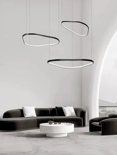 a modern living room with black and white furniture on the floor, round lights hanging from the ceiling