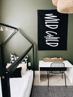 a black and white bedroom with a bed, desk, and hanging light fixture in the corner