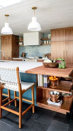 a kitchen with blue walls and wooden cabinets, two chairs at the center of the room