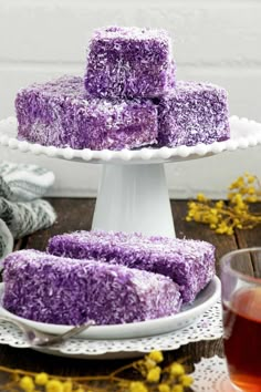 purple rice krispy treats stacked on a white cake plate with flowers in the background