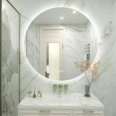 a bathroom with marble counter tops and a round mirror on the wall over the sink