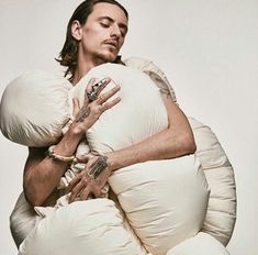 a man with tattoos on his arm and arms wrapped around an inflatable pillow