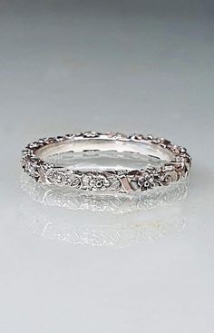 a white gold wedding ring with diamonds on it's sides and an intricate band