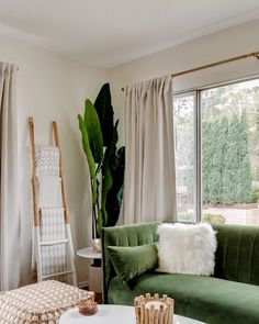 a living room with green velvet couches and white rugs on the coffee table