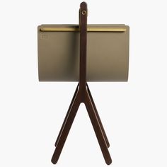 a wooden stand with a brown leather case on it's side and a gold metal object in the middle